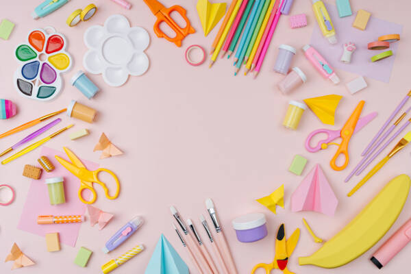 Pink pastel background with various colorful material for creativity and art activity. Stationery and supplies for drawing and craft with copy space. Primary School or kindergarten.