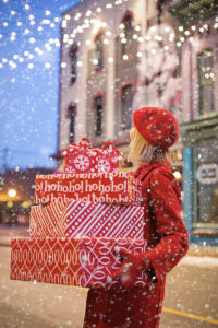 Lady holding Christmas presents in boxes whilst standing in a street
