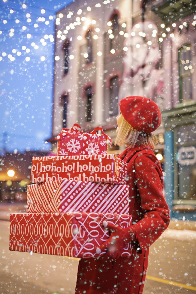 Lady holding Christmas presents in boxes whilst standing in a street